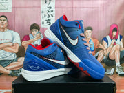 Angled display of the blue and red basketball sneakers showing the side branding, white outsole, and textured tread.
