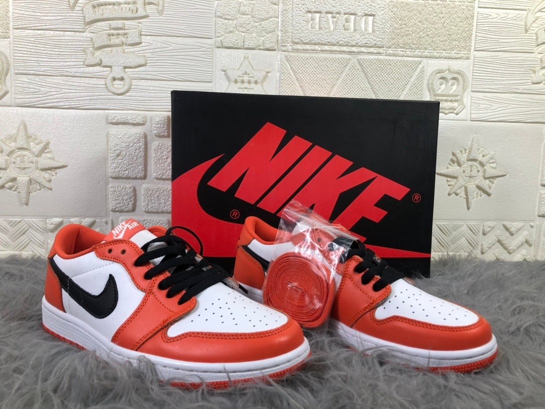 Pair of white, orange and black low-top sneakers displayed with a black Nike shoebox and an extra orange lace set.