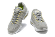 Pair of gray Nike Air Max 95 sneakers viewed from the front, with pale yellow lace details and volt-green lining.