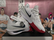 Two white basketball shoes displayed at an angle, showing black side Swooshes and red outsole details.