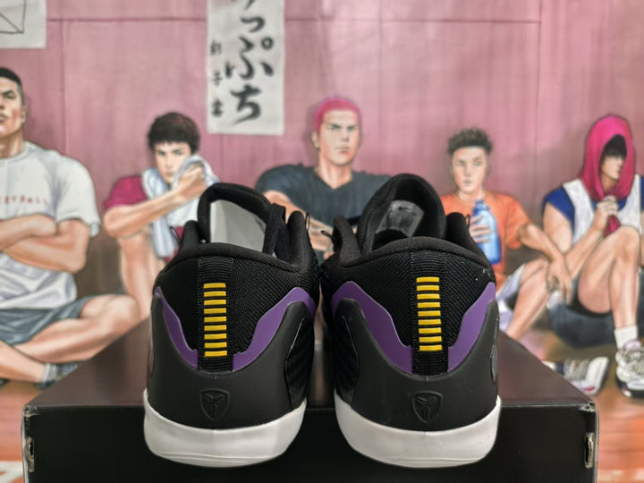 Rear view of black Nike basketball sneakers with purple heel accents, yellow vertical detailing, and white outsoles.