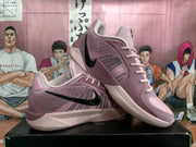 Angled view of the pair showing black side Swooshes, pink uppers, lace closure, and textured side panels.