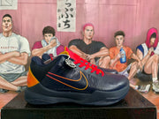 Side view of a navy basketball shoe with orange logo detailing, red laces, and an orange heel panel.