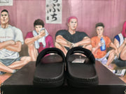 Rear view of the black slides showing the footbeds, heel area, and embossed lettering on the sole.