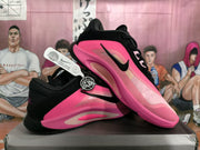 Angled side view showing the black Nike swoosh, pink upper, black collar, and contrasting midsole details.