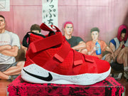 Side view of a red high-top Nike LeBron shoe with straps and a speckled white sole