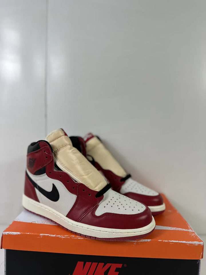 Pair of red, white, and black high-top sneakers displayed on an orange shoebox.
