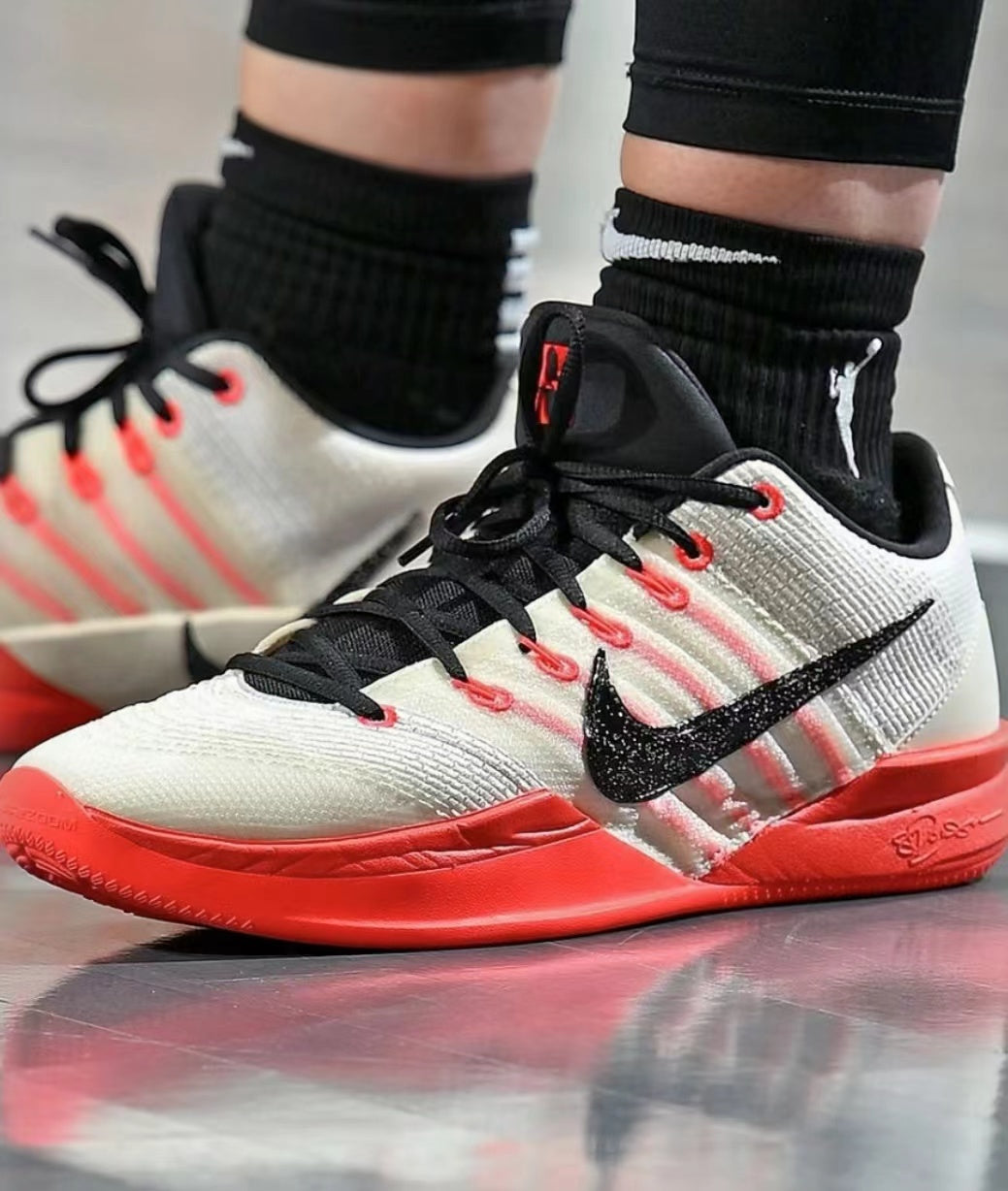 Pair of white, black and red Nike basketball-style sneakers with black laces and red outsole accents.