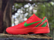 Side view of a red Nike Kobe 6 shoe with green swoosh and heel accents
