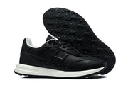 Black low-top sneaker with tonal side logo and white midsole, shown with its treaded outsole.