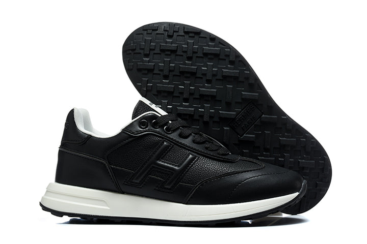 Black low-top sneaker with tonal side logo and white midsole, shown with its treaded outsole.