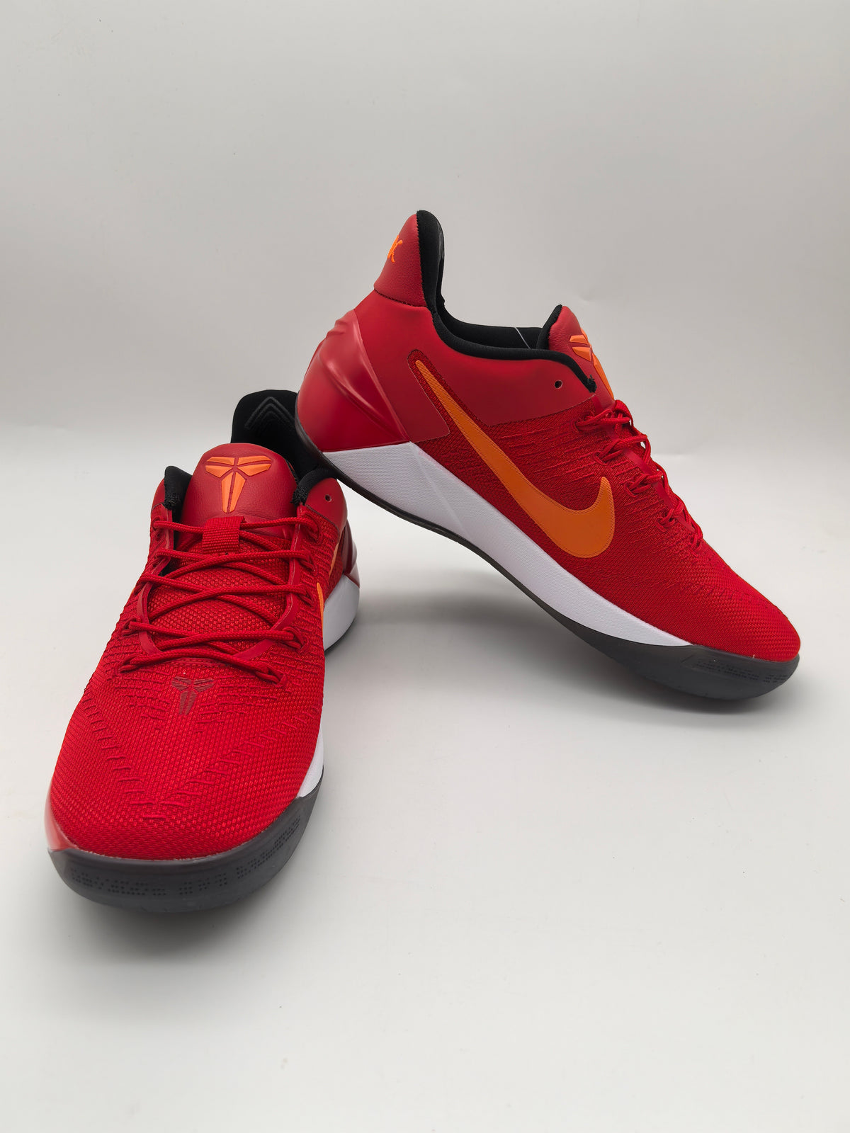 Two red Nike basketball sneakers with orange Swoosh branding, white midsoles, and black outsoles shown from angled views.