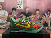 Side view of the orange-green patterned sneaker showing a lime-green Nike swoosh, dark green heel section and speckled green outsole.