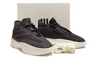 Pair of black low-top sneakers displayed in front of a light box with coiled laces.
