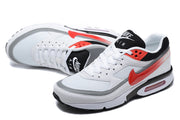 Angled view of white and red Nike Air Max sneakers with mesh panels and lace-up fronts