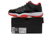 Side view of a black, white, and red low-top sneaker displayed on a black shoebox; the box label visibly shows a 5Y sample size.
