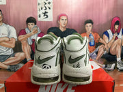 Rear view of off-white Nike sneakers with dark green accents, panda graphics, and speckled soles.