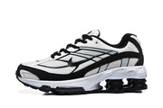 Side view of a white and black Nike Shox R4 sneaker with mesh-look panels and pod-style sole.