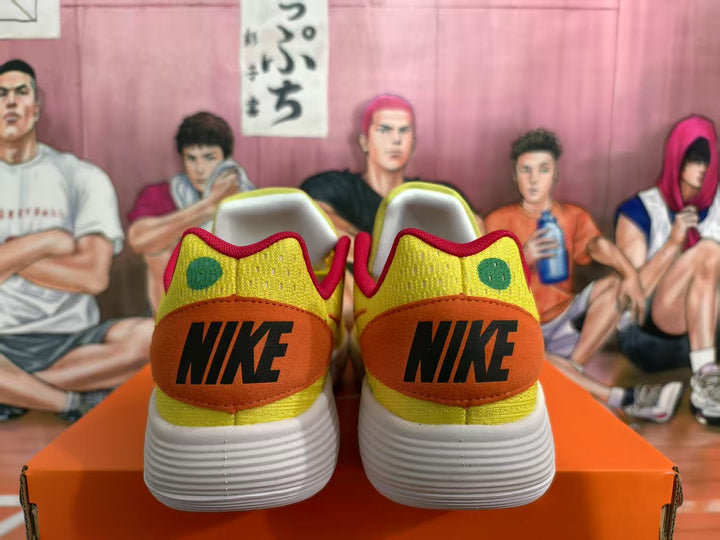 Rear view of yellow Nike sneakers with orange heel panels, black branding, green dot details, and white textured outsoles.