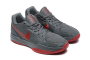 Angled front view of the dark gray and red sneaker pair showing laces, textured toe panels, and red accents.