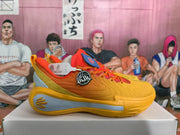 Side profile of an orange Curry basketball shoe with textured panels, a sculpted light gray midsole section and visible Curry branding.