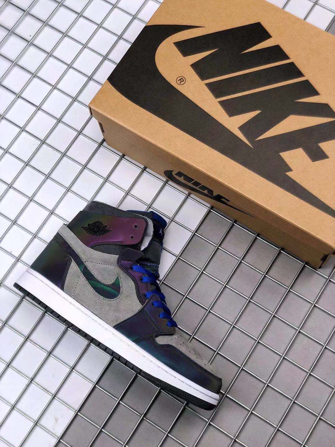 Air Jordan 1 Zoom high-top sneaker beside a Jordan-branded shoe box, showing gray, black, blue and iridescent accents.