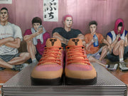 Front view of the Nike basketball sneakers showing orange laces, black tongue logos, pink textured uppers, and black outsoles.
