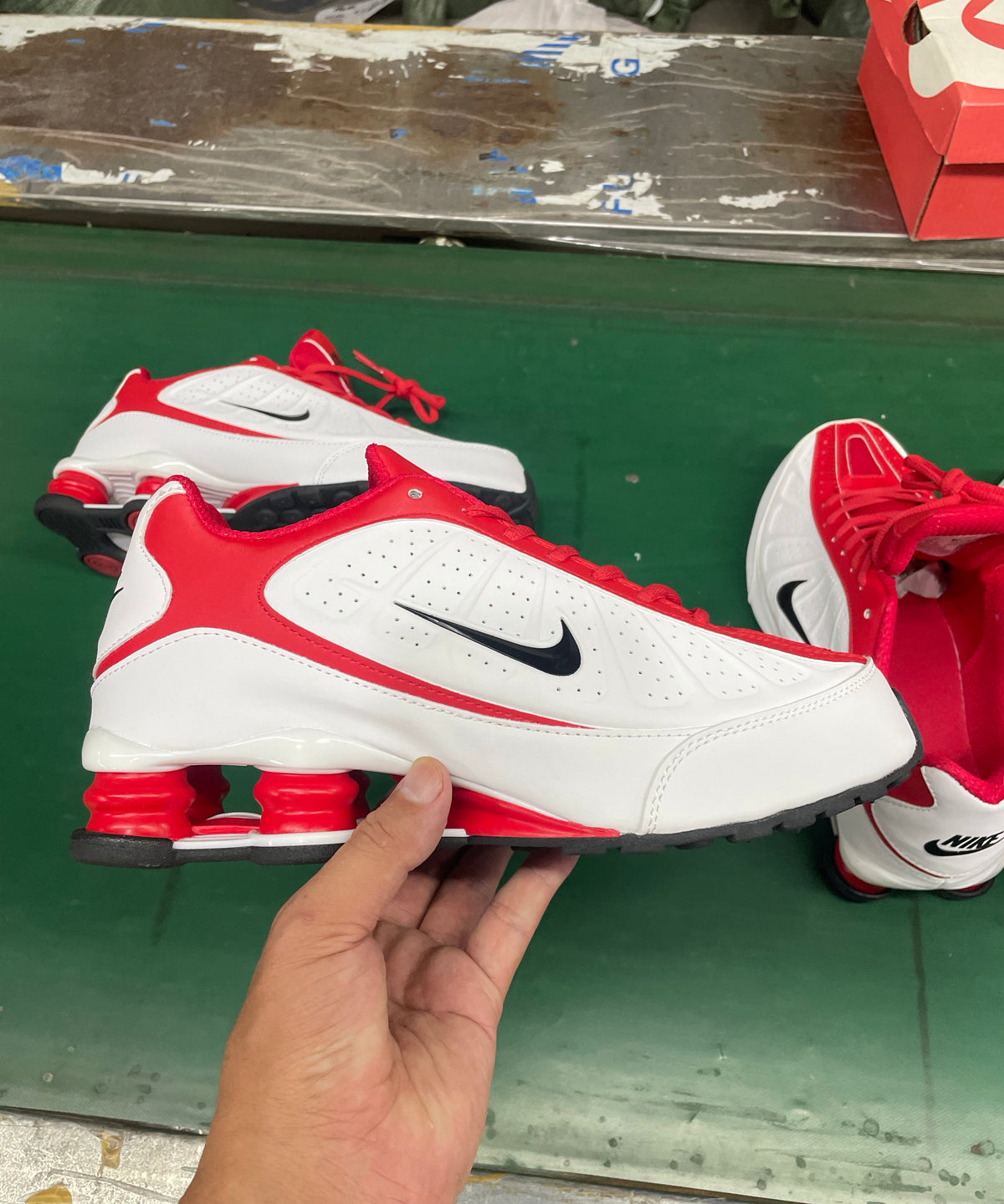 White and red Nike low-top sneakers with black Swoosh details and visible heel cushioning columns.