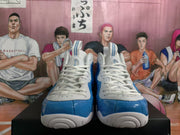 Front view of the white and blue sneakers showing the laces, blue toe panels, and textured white outsoles.