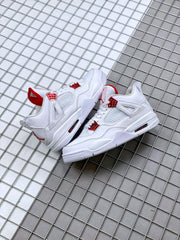 Pair of white and red Air Jordan 4 sneakers arranged on a gridded surface.