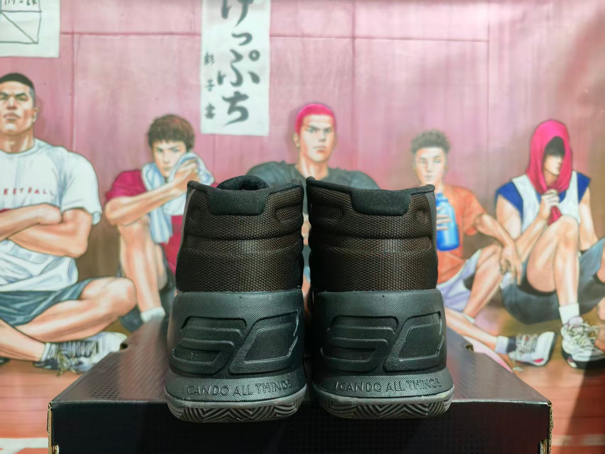 Rear view of black high-top basketball sneakers showing padded collars, textured heel panels, patterned outsoles, and “I CAN DO ALL THINGS” text on the heels.