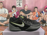 Side view of a black basketball sneaker with a contrasting swoosh-shaped mark, black laces, grey midsole details, and a glossy side overlay.