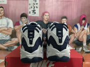Rear view of white and dark blue Nike sneakers showing the padded heels, dark pull tabs, and two-tone outsoles.