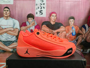 Side profile of an orange low-top sneaker showing the lace-up upper, Jumpman midsole logo, and visible Zoom marking near the toe.