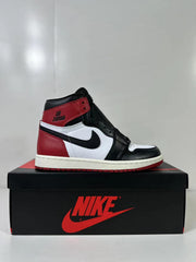 Side profile of one black, white, and red high-top sneaker on its shoebox.