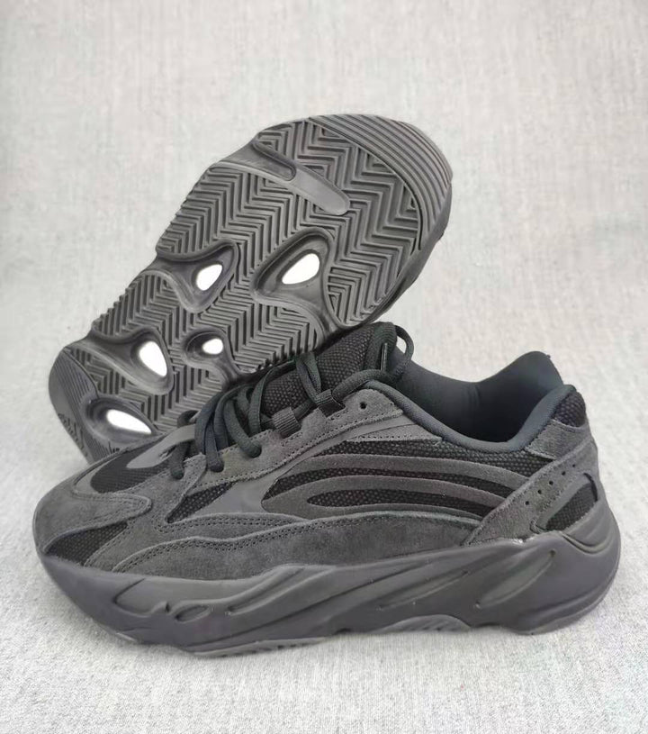 Charcoal and gray 700 V2 sneaker shown from the side with the outsole visible behind it.