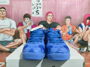 Front view of blue Nike basketball sneakers with red and white accents on a shoebox.