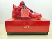 Side profile of a red sneaker displayed on a red presentation box with a decorative hangtag.