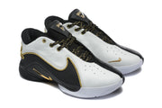 Three-quarter view of the black and white sneakers highlighting the perforated toe panels, padded collars, and gold details.