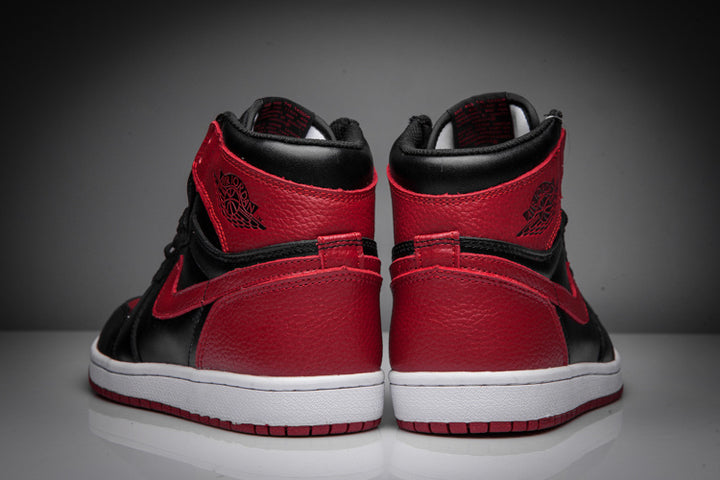 Rear view of black and red high-top sneakers showing red heel panels, black collars, ankle branding, and white midsoles.