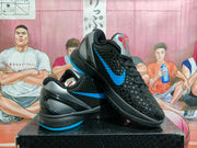 Angled view of the black and blue sneakers showing the side detailing, textured upper, gray heel panel, and blue outsole edge.