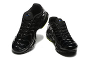 Front three-quarter view of black Nike Air Max Plus sneakers with glossy patterned overlays.