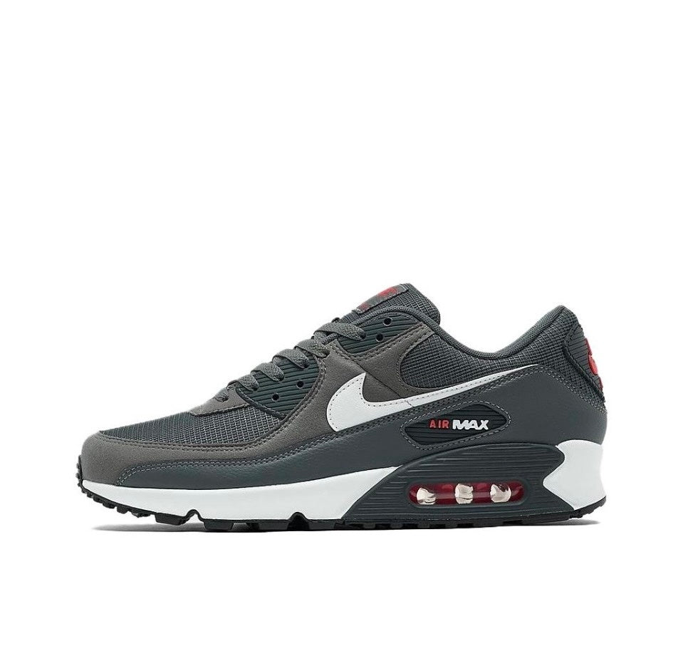 Side view of a dark grey Nike Air Max 90 sneaker with a white Swoosh and midsole and red accents