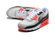 Pair of Nike Air Max 90 sneakers in grey, black, white, and bright crimson, shown from above and at an angle.
