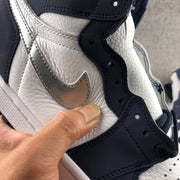 Close-up of the textured white side panel, silver Swoosh and navy eyelet panel.