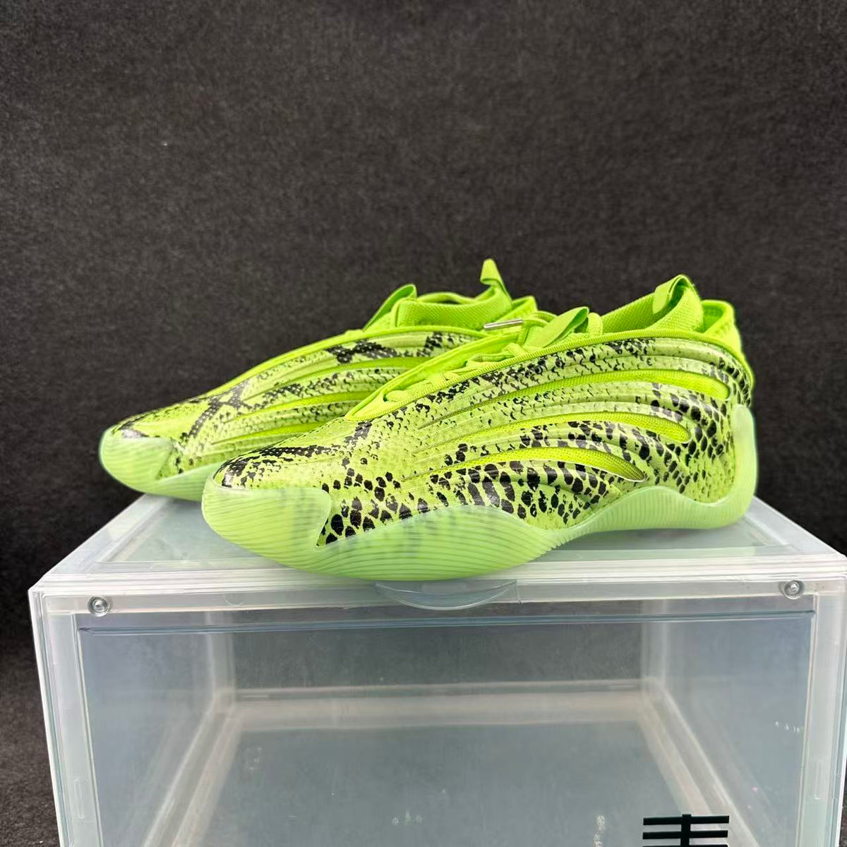 Pair of lime-green low-profile sneakers with black snake-like patterning, shown from the side