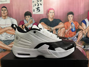 Side profile of a white and black Jordan sneaker showing the textured upper, glossy black forefoot panel, layered sole, and visible air-cushion window.