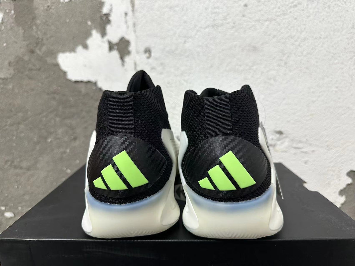 Rear view of black basketball shoes with white midsoles and neon-green Adidas heel logos.