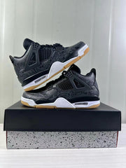 Pair of black Air Jordan 4 sneakers arranged on a shoebox, showing the side cages, tonal patterned upper, white midsoles, and gum outsoles.