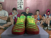 Front view of the matching green and red sneakers showing the patterned toe boxes and yellow laces.
